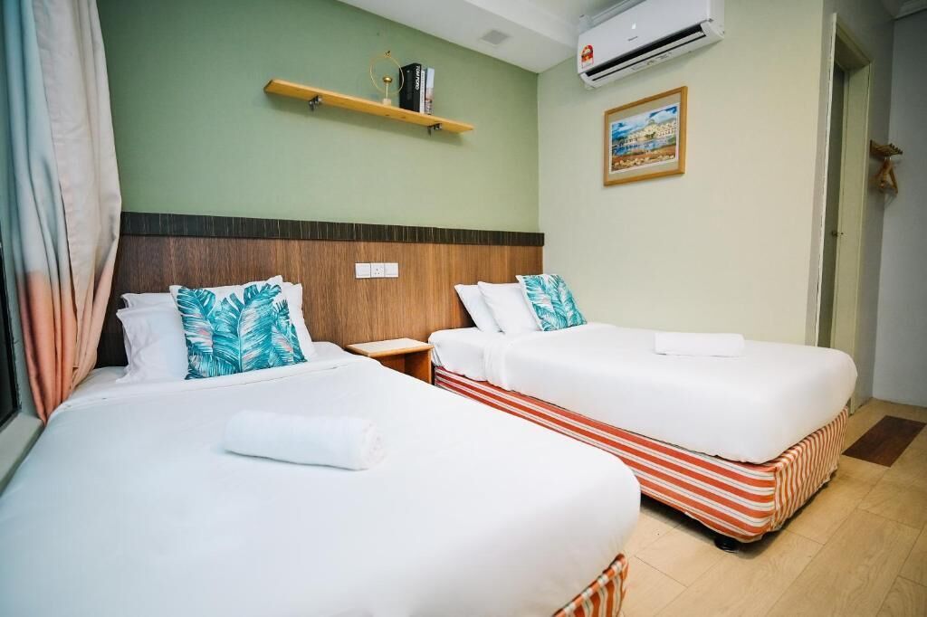 A hotel room with two beds, a wooden headboard, an air conditioner, a shelf with books, and a framed picture on the wall.