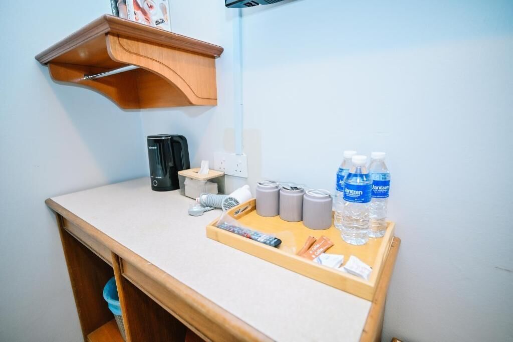 A small kitchenette with a coffee maker, a kettle, and water bottles on a tray.