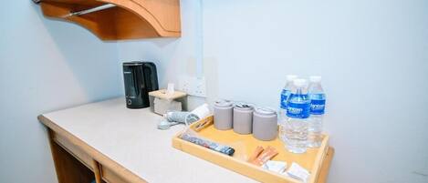 A small kitchenette with a coffee maker, a kettle, and water bottles on a tray.