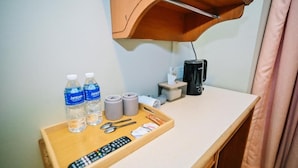 A hotel room with a wooden tray table holding a remote control, two water bottles, a pair of glasses, and a tissue box. - Swing & Pillows at Chinatown (Kuala Lumpur)