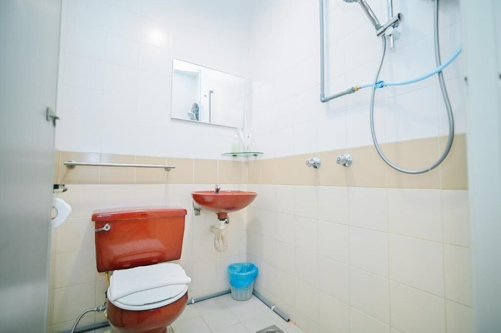 A small bathroom with a toilet, sink, and shower.