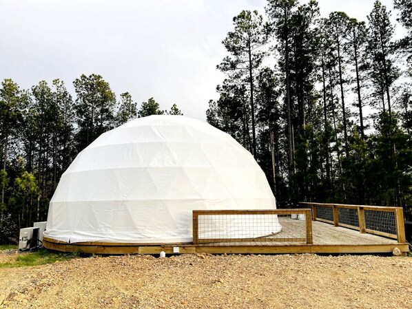 Una gran estructura en forma de cúpula blanca con una terraza de madera al frente.