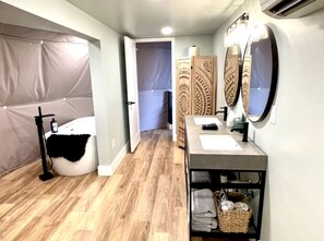 A bathroom with a bathtub, a vanity with a mirror, and a shower area. - Spacious Dome with Lofted Interior and Furnished Deck in Kentucky (Cadiz)