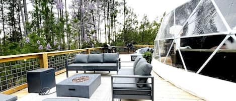 Una terrazza con mobili da esterno, un braciere e una struttura in vetro.