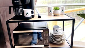 A kitchen area with a Keurig coffee maker, a microwave, and a stack of plates on a table. - Spacious Dome with Lofted Interior and Furnished Deck in Kentucky (Cadiz)
