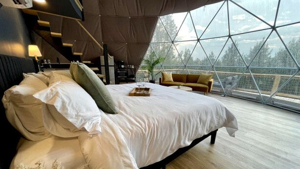 A modern bedroom with a large bed, a sofa, and a dining table. - Spacious Dome with Lofted Interior and Furnished Deck in Kentucky (Cadiz)