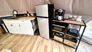 Una cocina compacta con refrigerador, cafetera y estantes de almacenamiento.