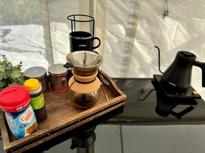 A coffee maker, a coffee pot, a coffee filter, and a coffee mug on a wooden tray.