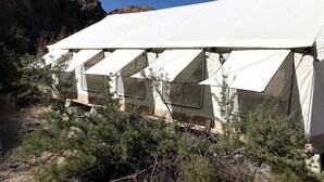 A row of white tents with a rocky cliff in the background.
