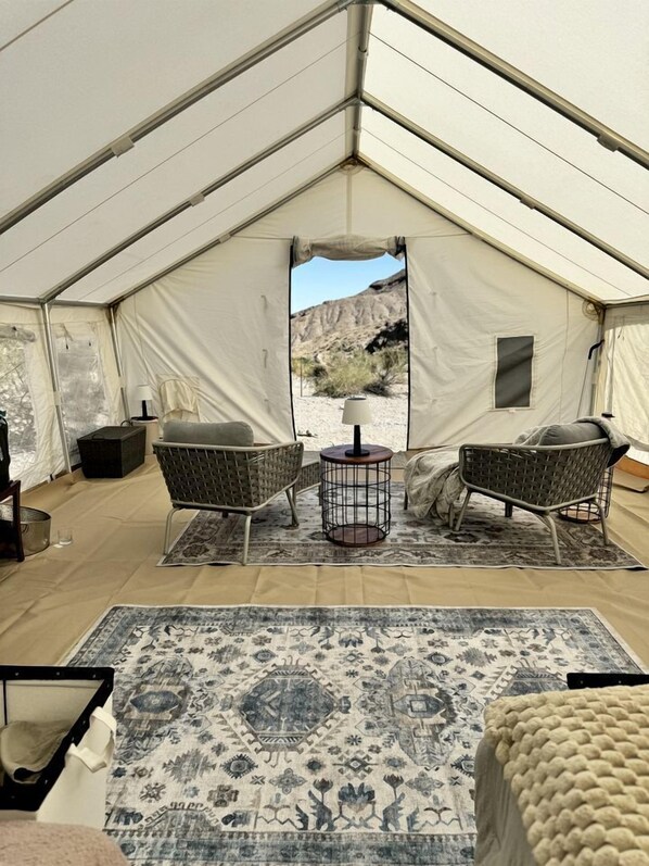 A tent with two wicker chairs, a small round table, and a patterned rug.