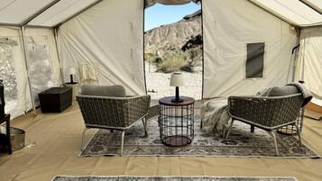 A tent with two wicker chairs, a small round table, and a patterned rug.