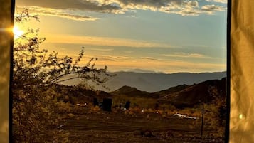 A landscape with a clear sky, distant mountains, and sparse vegetation.