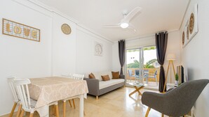 Un espace repas comprenant une table, des chaises, un canapé et un ventilateur de plafond.