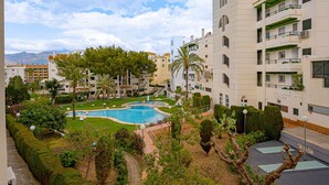 Un immeuble résidentiel doté d’une piscine, entouré de verdure et de palmiers.