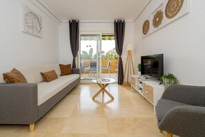 Un salon avec un canapé, un téléviseur, une petite table et un balcon offrant une vue agréable.