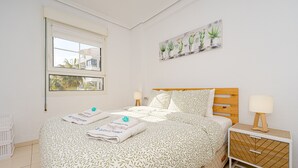Une chambre à coucher comprenant un lit, une table de chevet, une fenêtre et une œuvre d’art murale.