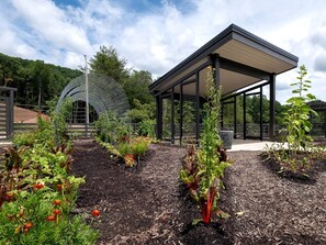 A garden with a gazebo, a metal sculpture, and various plants.