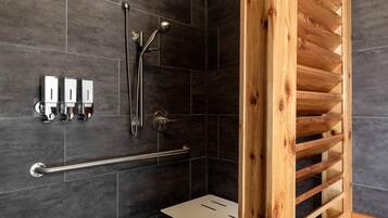 Un baño moderno con baldosas oscuras, un box de ducha de madera, un pasamanos y un pequeño banco.