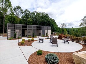 A modern building with a covered outdoor seating area, surrounded by landscaped gardens and trees.