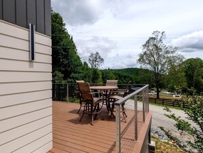 Terraza con mobiliario exterior, barandilla y vistas a un paisaje rural.