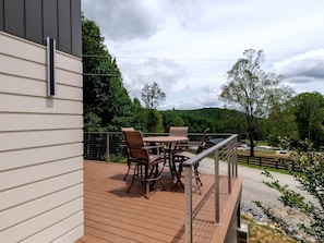 Une terrasse dotée de mobilier d’extérieur, d’une rambarde et offrant une vue sur un paysage rural.