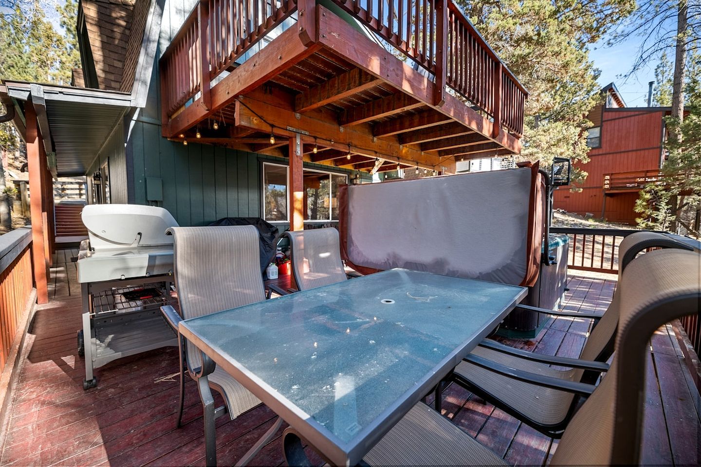 Um deck externo com mesa, cadeiras e churrasqueira.