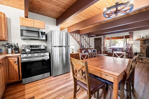 Une cuisine moderne dotée d’appareils électroménagers en acier inoxydable, d’un plancher en bois et d’un coin repas avec une grande table et des chaises en bois.