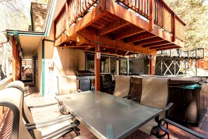 Eine Terrasse im Freien mit einem Metalltisch und -stühlen, einem Grill und einer überdachten Sitzgelegenheit.