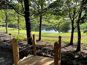 A wooden bridge over a pond with a stone wall and trees in the background.