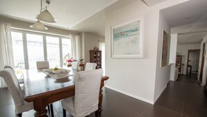 A dining area with a wooden table, white chairs, and a painting on the wall. - Room 'Stanza in Villa Magica' with Wi-Fi and Air Conditioning (Credaro)