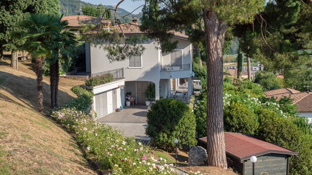 A two-story house with a balcony, surrounded by trees and a garden. - Room 'Stanza in Villa Magica' with Wi-Fi and Air Conditioning (Credaro)