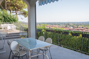 A balcony with a table and chairs, a view of a cityscape, and a metal railing. - Room 'Stanza in Villa Magica' with Wi-Fi and Air Conditioning (Credaro)