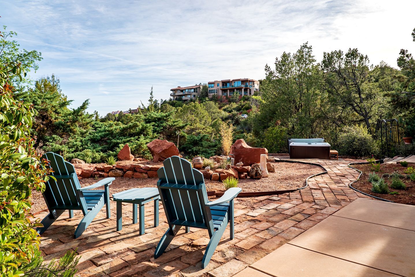 Een terras met Adirondack stoelen, een jacuzzi en een pad van stenen.