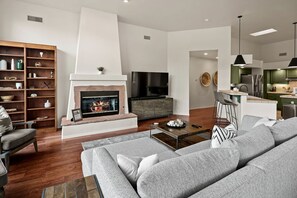 A modern living room with a fireplace, a television, a sofa, and a kitchen area. - Intimate Wonderful Rental with Jacuzzi in Arizona (Sedona)
