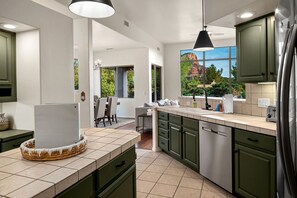 A modern kitchen with green cabinets, a large window with a view, and a dining area with a table and chairs. - Intimate Wonderful Rental with Jacuzzi in Arizona (Sedona)