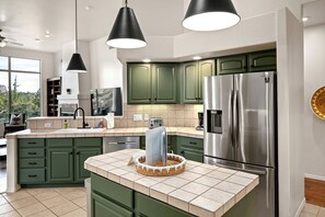 A modern kitchen with green cabinets, stainless steel appliances, and pendant lighting. - Intimate Wonderful Rental with Jacuzzi in Arizona (Sedona)