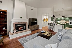 A modern living room with a fireplace, a sofa, a coffee table, and a kitchen area with green cabinets. - Intimate Wonderful Rental with Jacuzzi in Arizona (Sedona)