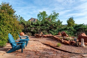 A patio with blue Adirondack chairs, a stone wall, and a view of a mountain range. - Intimate Wonderful Rental with Jacuzzi in Arizona (Sedona)