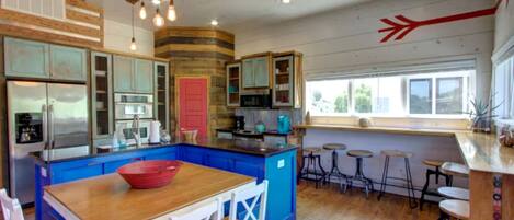 Una cocina con armarios azules, una isla de madera y una puerta roja.