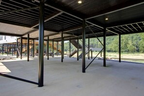 A large, open indoor space with a metal framework and concrete floor, surrounded by trees and a building with a staircase. - Stunning Elevated Cabin on the Caddo River for a Peaceful Getaway with Gorgeous Views in Glenwood, Arkansas (Glenwood)