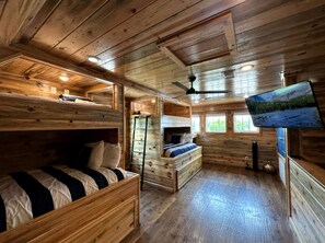 Eine Hütte mit Etagenbetten, einer Strickleiter, einem Deckenventilator und einem Fernseher.