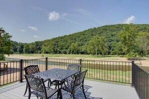 Eine Terrasse mit Tisch und Stühlen, mit Blick auf einen Fluss und bewaldete Hügel.