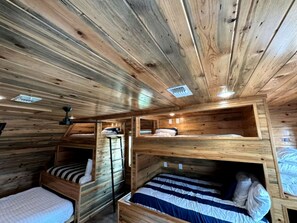 A cabin with bunk beds, wooden walls, and a sloped ceiling. - Stunning Elevated Cabin on the Caddo River for a Peaceful Getaway with Gorgeous Views in Glenwood, Arkansas (Glenwood)