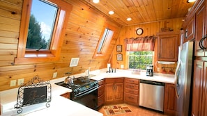 Una cocina con paredes de madera, estufa, lavavajillas y refrigerador.
