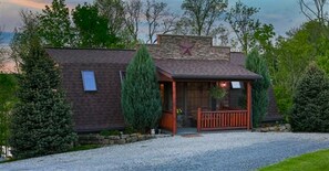 Una casa con fachada de piedra, un porche de madera y un camino de entrada de grava.