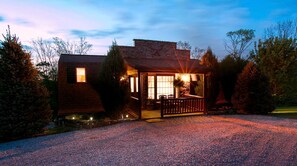 A rustic cabin with a porch, a stone chimney, and a gravel driveway. - Romantic Forest Cabin with Amazing Private Deck and Spa in Ohio (Sugarcreek)