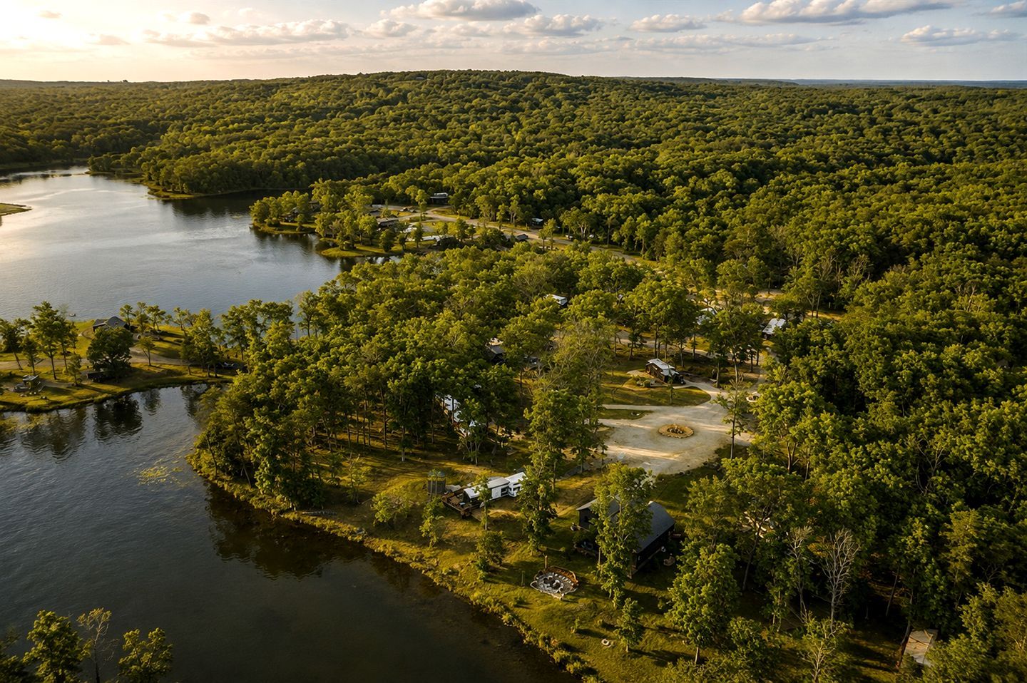 A lakeside property with a campground, surrounded by dense forest and hills.