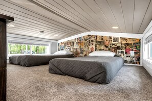 Un dormitorio con dos camas, techo inclinado y pared decorada con fotografías.