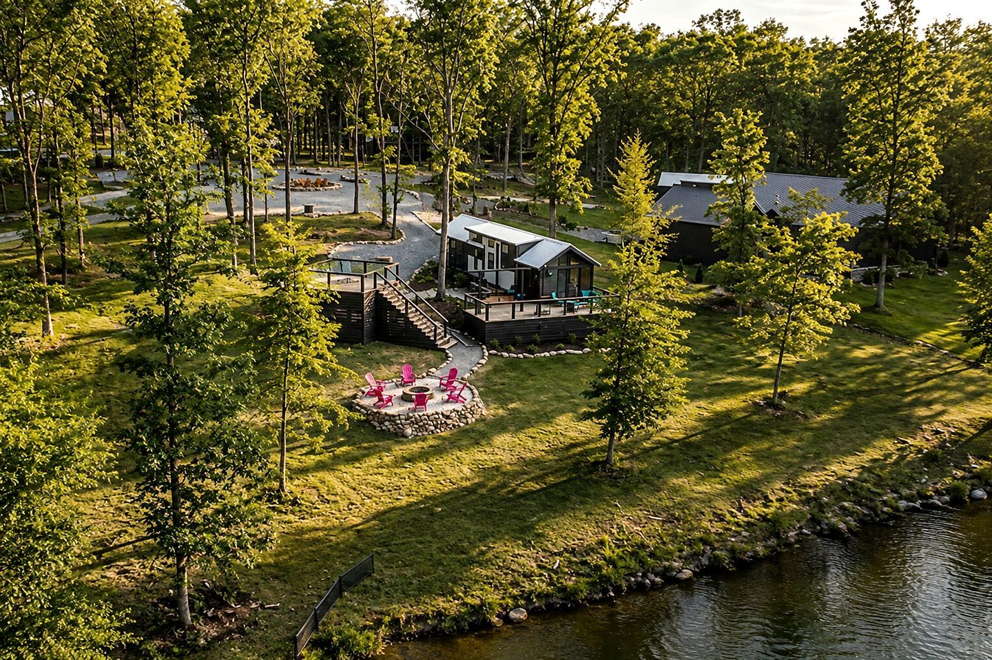 A lakeside cabin with a deck, a fire pit, and a small outdoor seating area.