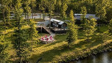 A lakeside cabin with a deck, a fire pit, and a small outdoor seating area.